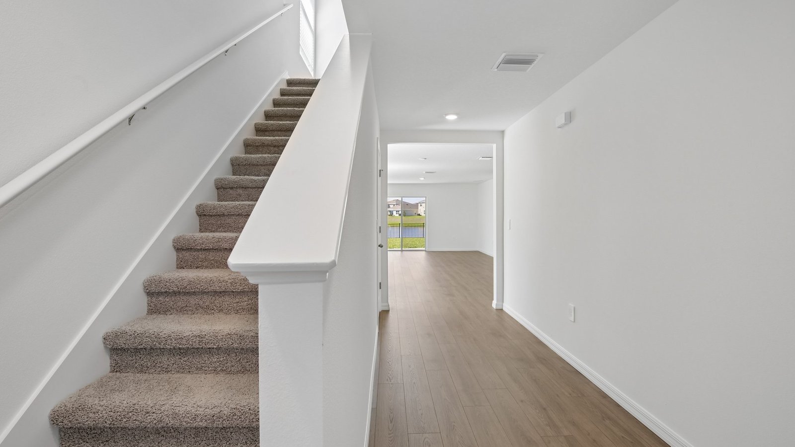 Home entry way thru the front door with LVP flooring and a view to the living space.