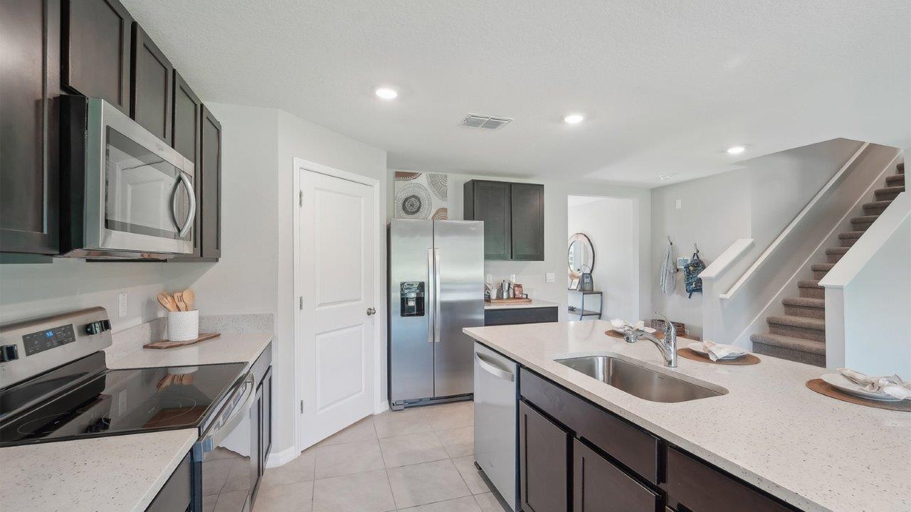 Kitchen with island seating, quartz counters, spacious pantry and stainless-steel appliances.