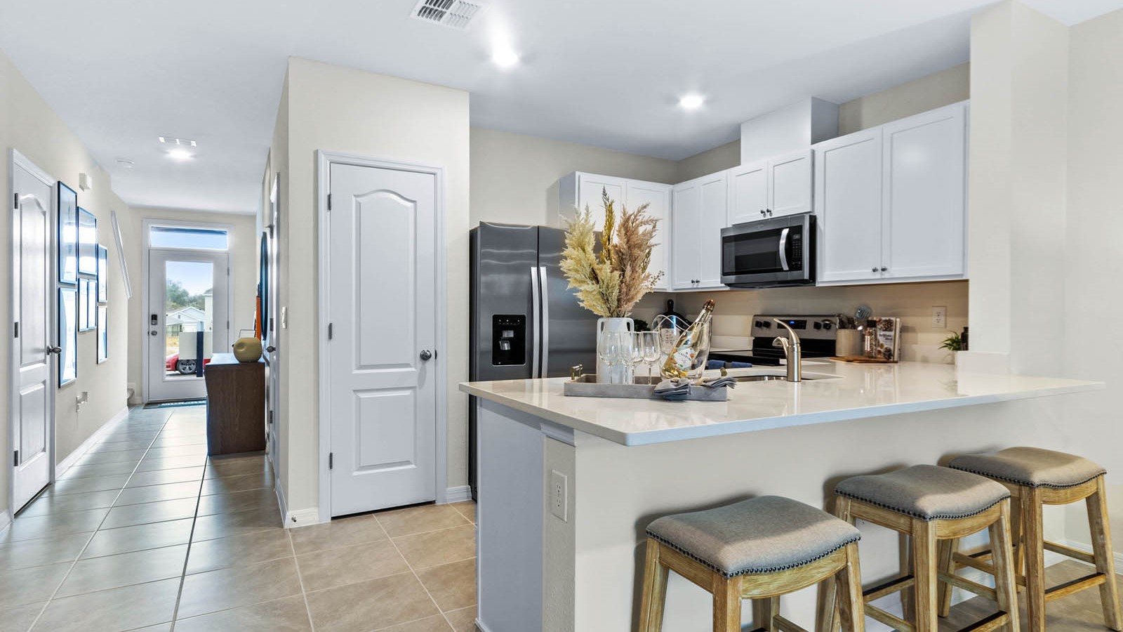 Kitchen with island seating, quartz counters, spacious pantry and stainless-steel appliances.