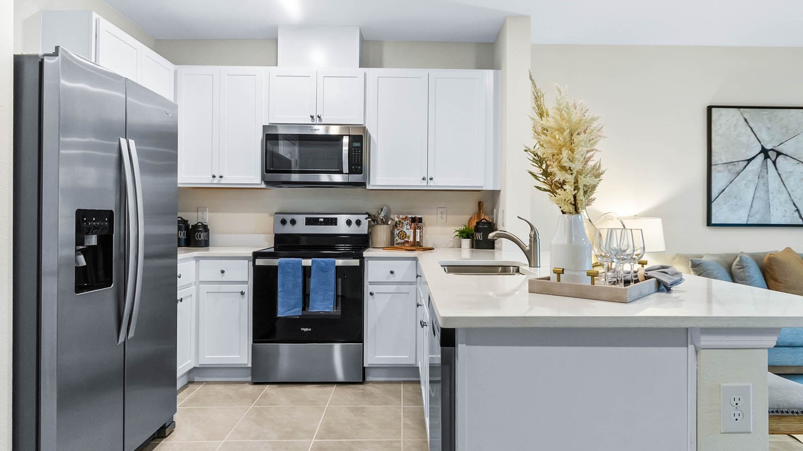 Kitchen with island seating, quartz counters, spacious pantry and stainless-steel appliances.