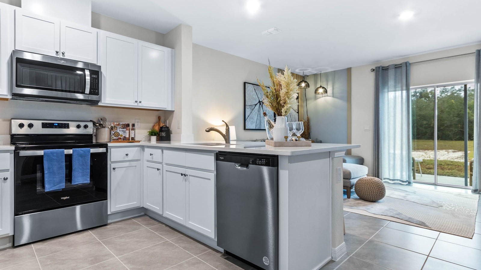 Kitchen with island seating, quartz counters, spacious pantry and stainless-steel appliances.