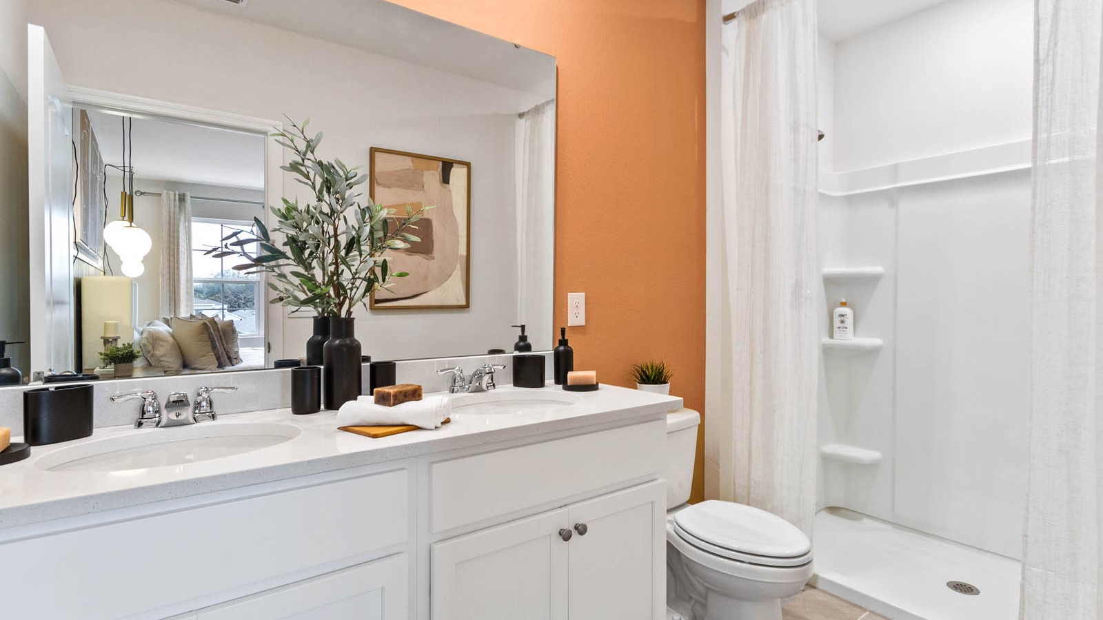 Modern bathroom with double vanity sinks, large wall mirror, cabinets and quartz countertops.