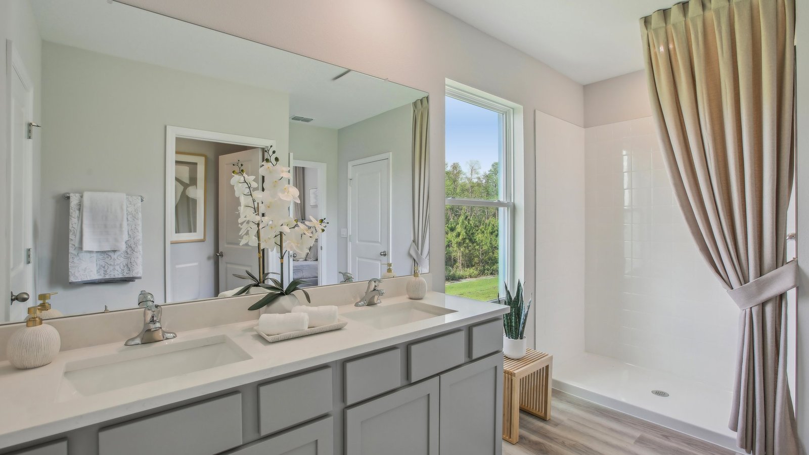 Modern bathroom with double vanity sinks, large wall mirror, cabinets and quartz countertops.