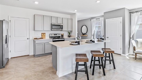 Central kitchen island anchors the home adding a dining option, full sink, pantry and storage, multi-prep zones