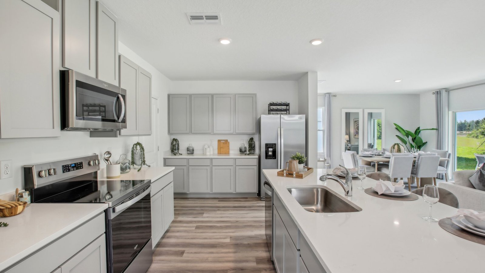 Kitchen with island seating, quartz counters, spacious pantry and stainless-steel appliances.