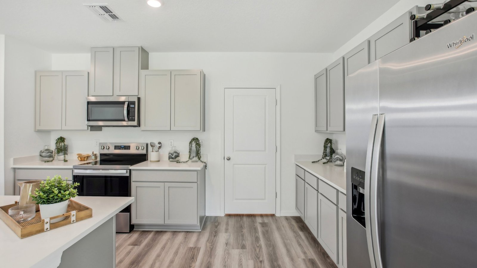 Kitchen with island seating, quartz counters, spacious pantry and stainless-steel appliances.