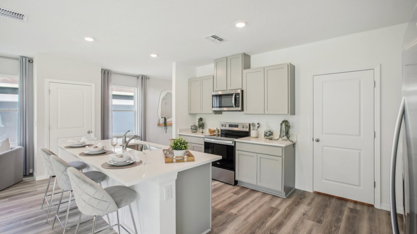 Kitchen with island seating, quartz counters, spacious pantry and stainless-steel appliances.