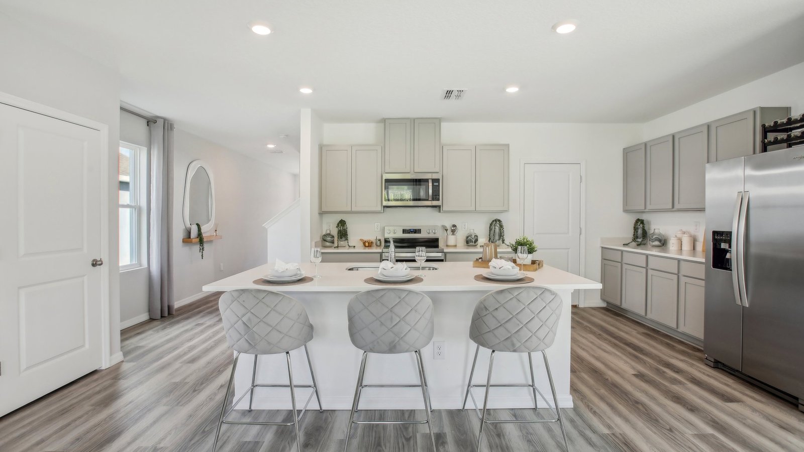 Kitchen with island seating, quartz counters, spacious pantry and stainless-steel appliances.