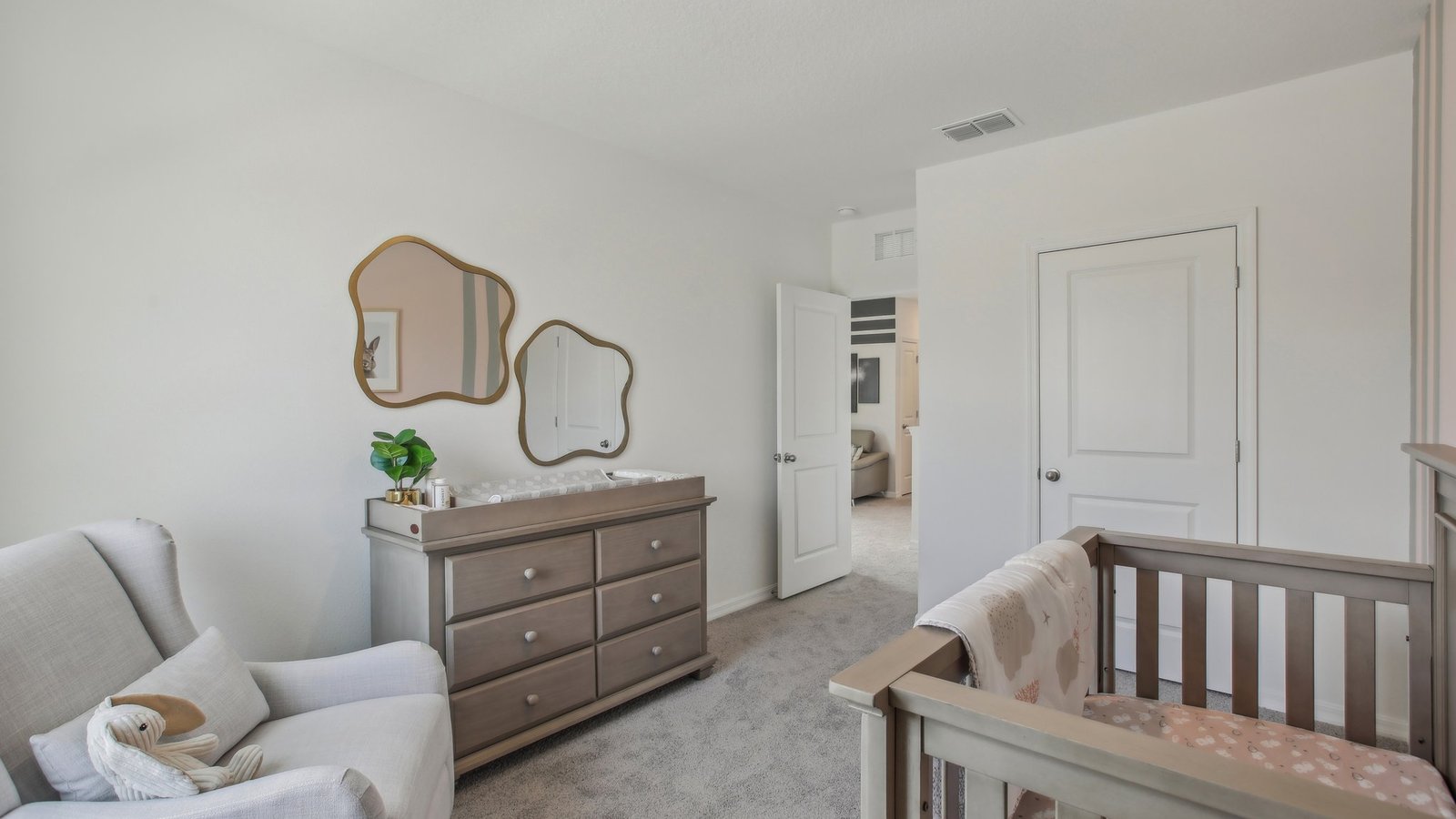 Child's nursery with crib, closet, soft seating and storage.