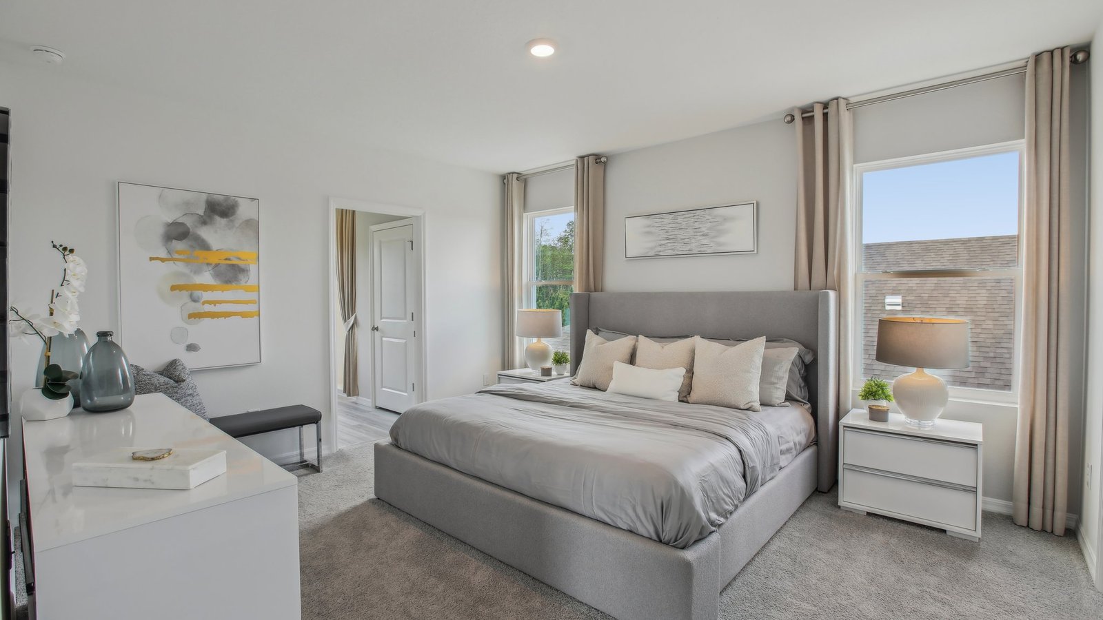 Spacious primary bedroom with king size bed, carpet flooring, natural lighting and a walk-in closet.