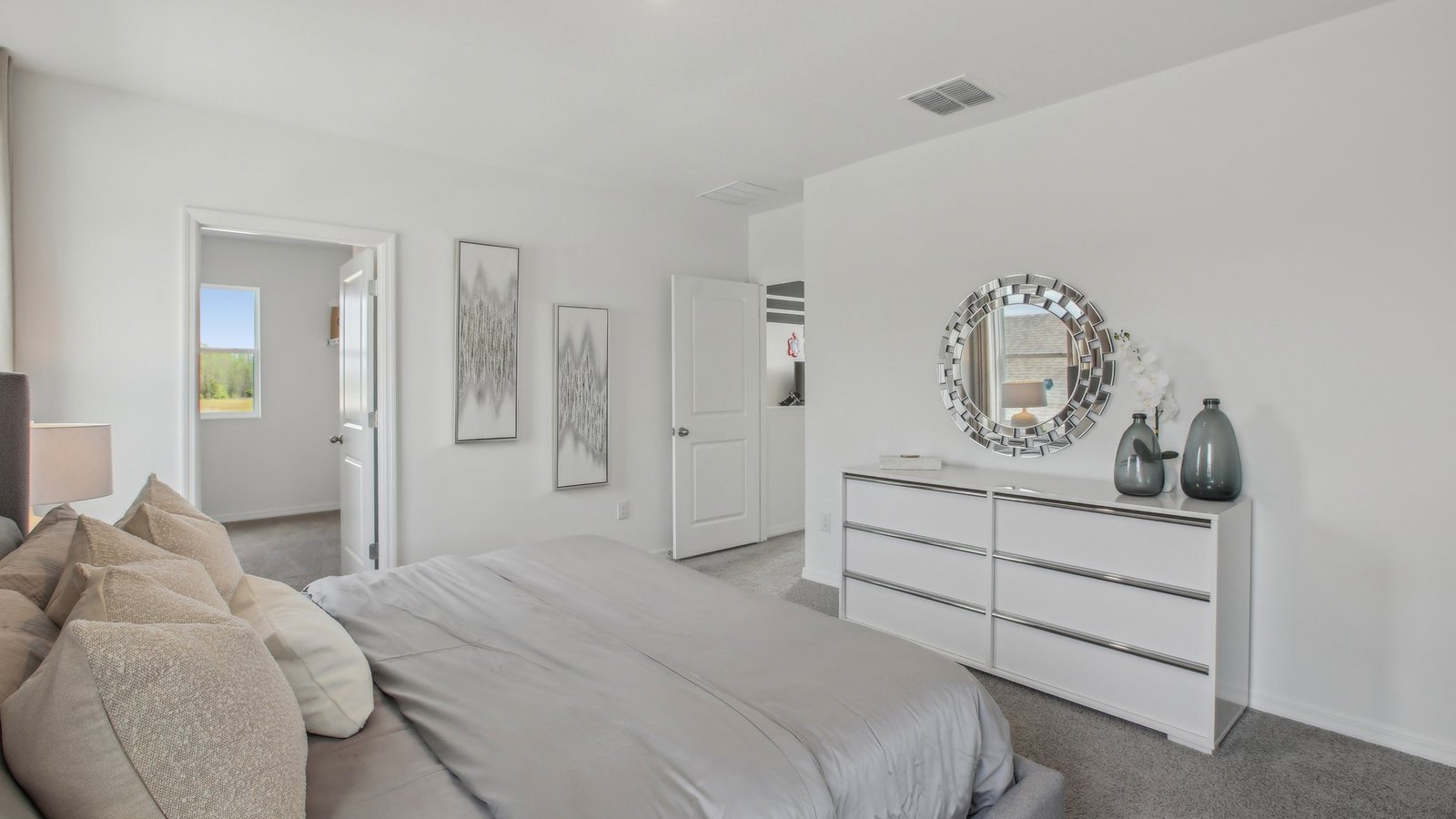 Spacious primary bedroom with king size bed, carpet flooring, natural lighting and a walk-in closet.