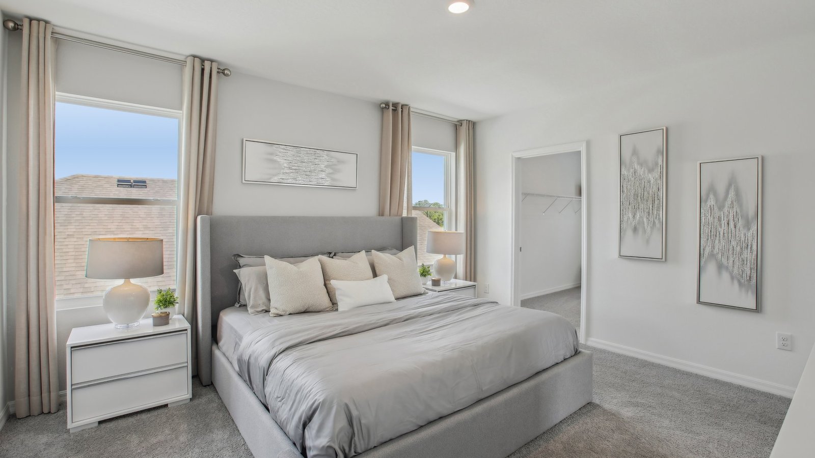 Spacious primary bedroom with king size bed, carpet flooring, natural lighting and a walk-in closet.