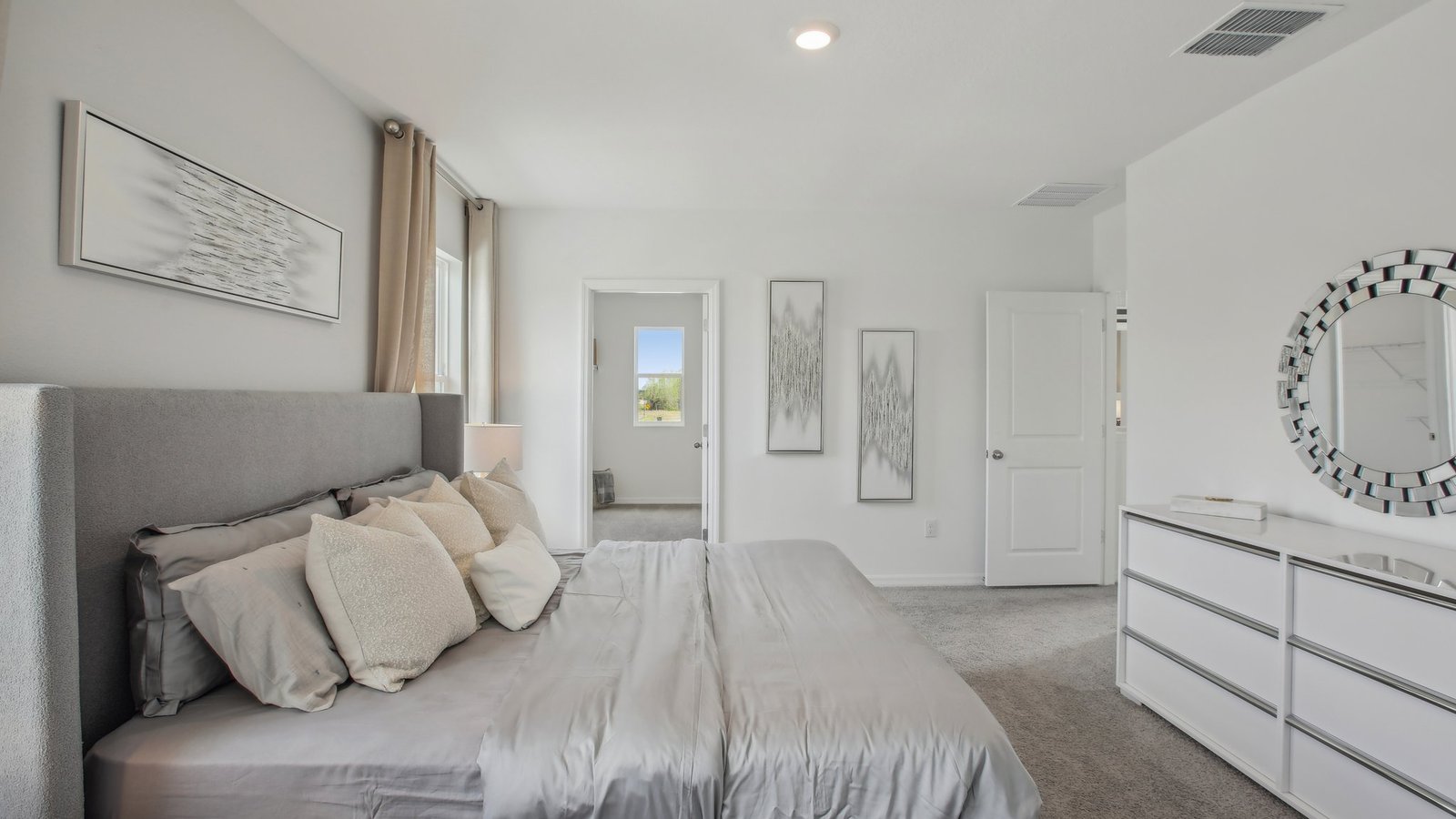 Spacious primary bedroom with king size bed, carpet flooring, natural lighting and a walk-in closet.