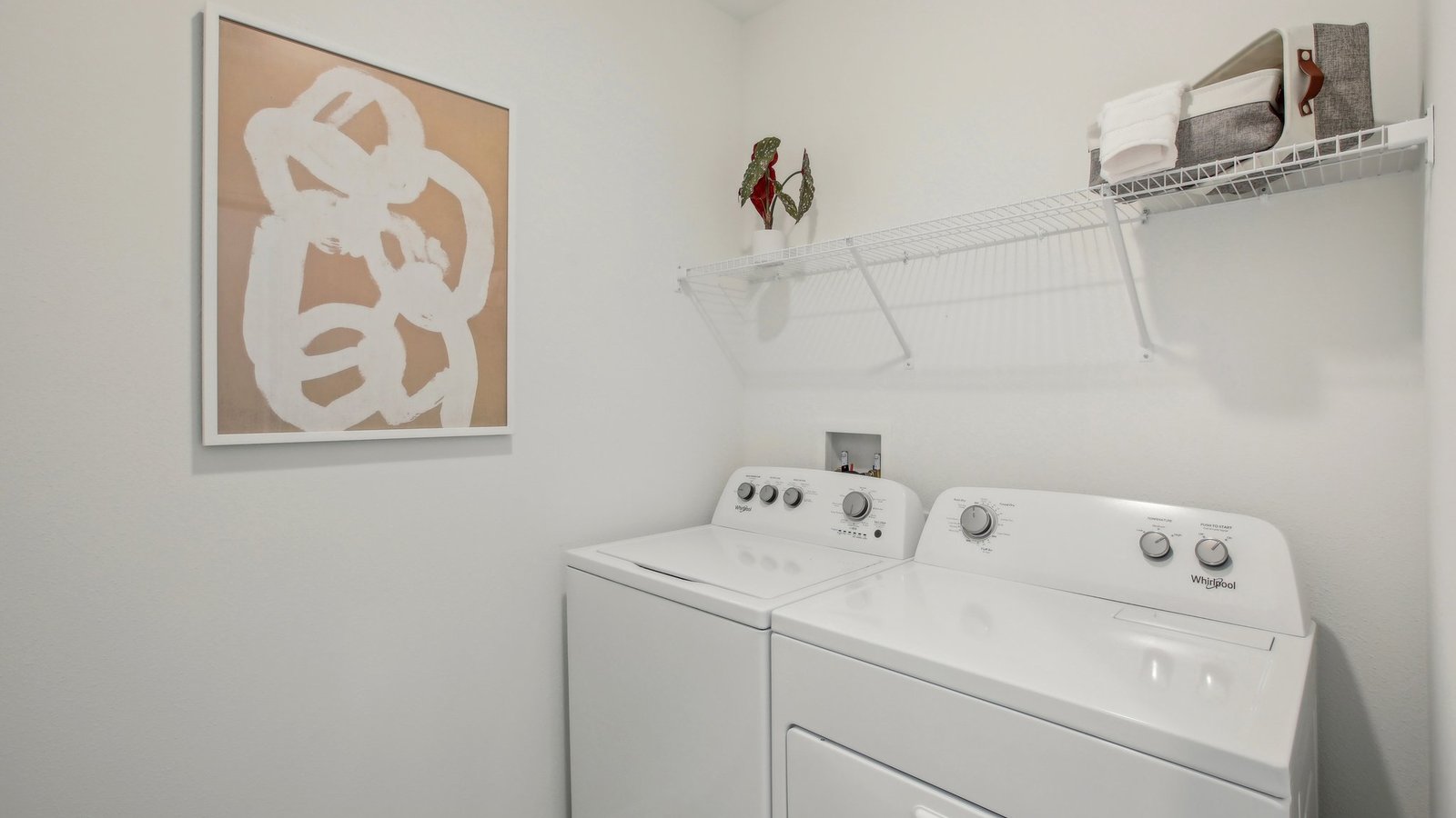 Laundry room with washer and dryer hookups and wall shelving.