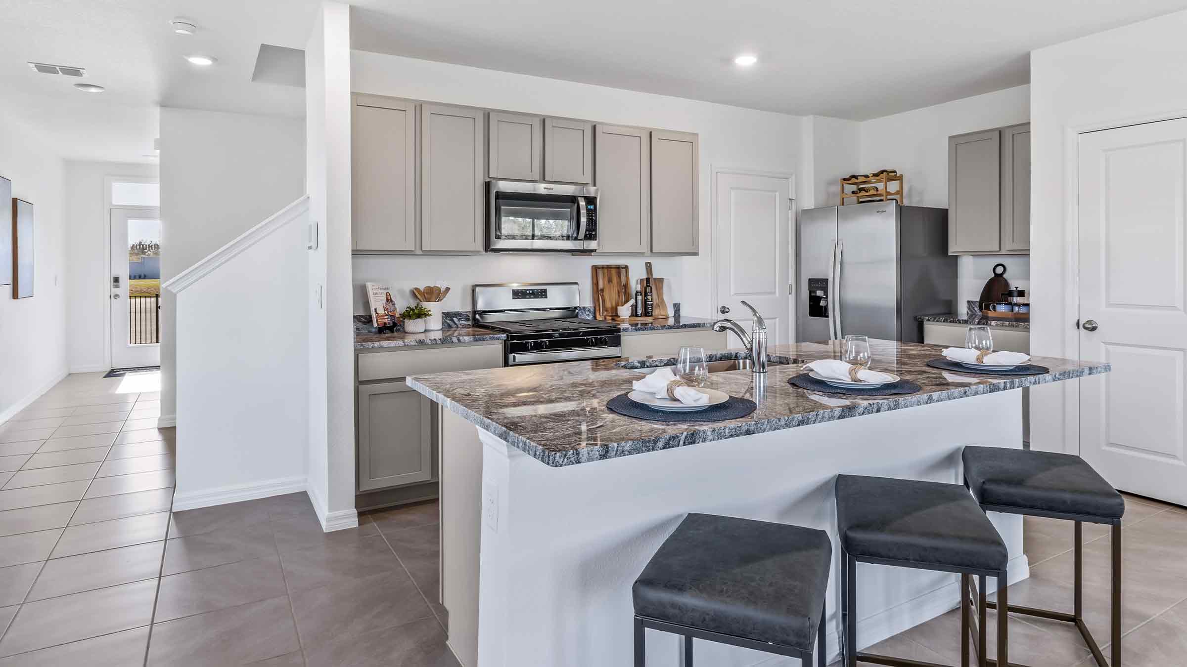 Kitchen with island seating, quartz counters, spacious pantry and stainless-steel appliances.