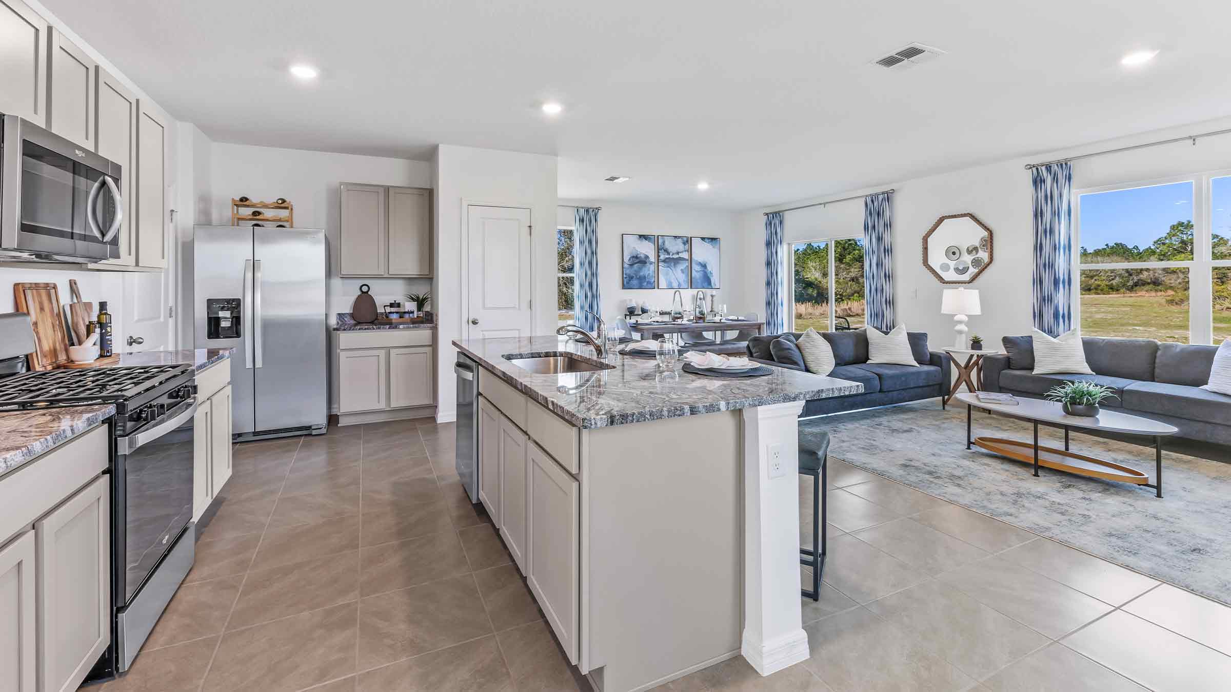 Kitchen with island seating, quartz counters, spacious pantry and stainless-steel appliances.