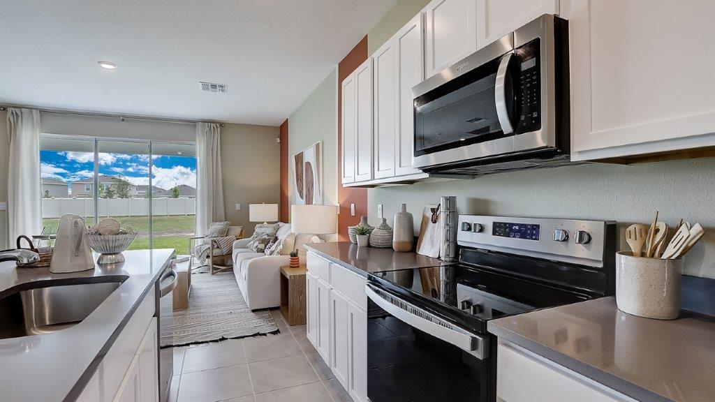 Kitchen with island seating, quartz counters, spacious pantry and stainless-steel appliances.