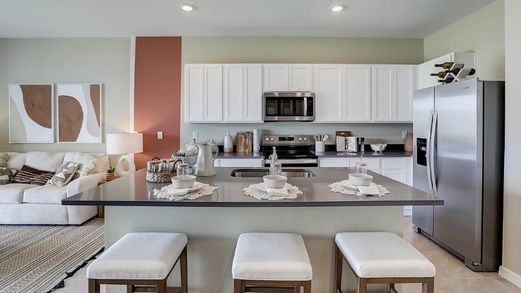 Kitchen with island seating, quartz counters, spacious pantry and stainless-steel appliances.