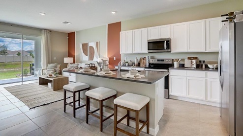 Kitchen with island seating, quartz counters, spacious pantry and stainless-steel appliances.