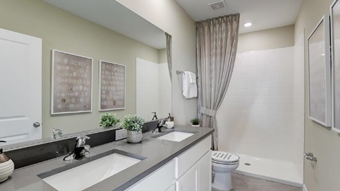 Modern bathroom with double vanity sinks, large wall mirror, cabinets and quartz countertops.