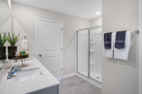 primary bathroom with walk in shower and dual vanity sinks