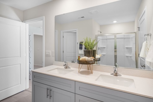 primary bathroom with walk in shower and dual vanity sinks