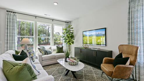 living room with light grey sofas, an accent chair and green decor