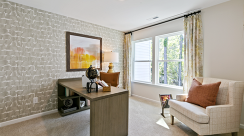 bedroom turned into a home office with grey wallpaper and orange accent decor