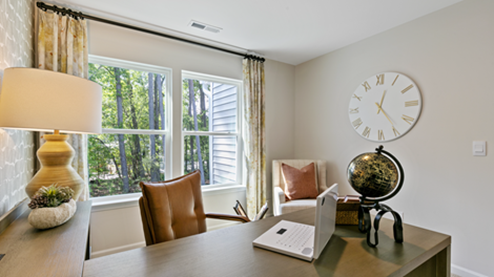 bedroom turned into a home office with grey wallpaper and orange accent decor