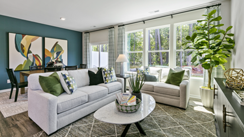 living room with light grey sofas, an accent chair and green decor