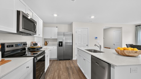kitchen with quartz counters, kitchen island, pantry, stainless steel appliances