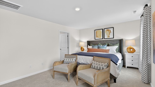 primary bedroom with two windows and carpeting, attached bath