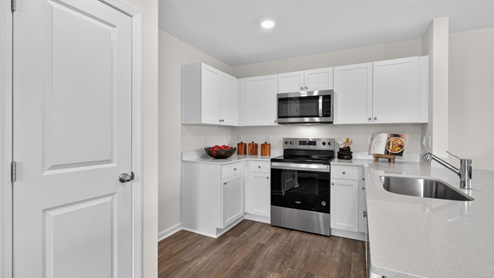 kitchen with quartz counters, kitchen peninsula, pantry, stainless steel appliances