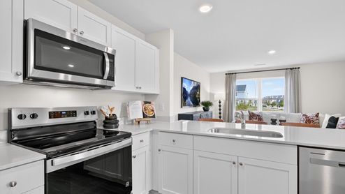 kitchen with quartz counters, kitchen peninsula, pantry, stainless steel appliances