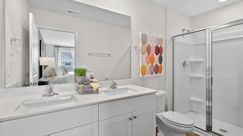 primary bathroom with walk in shower and dual vanity sinks