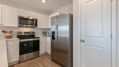 kitchen with quartz counters, kitchen island, pantry, stainless steel appliances