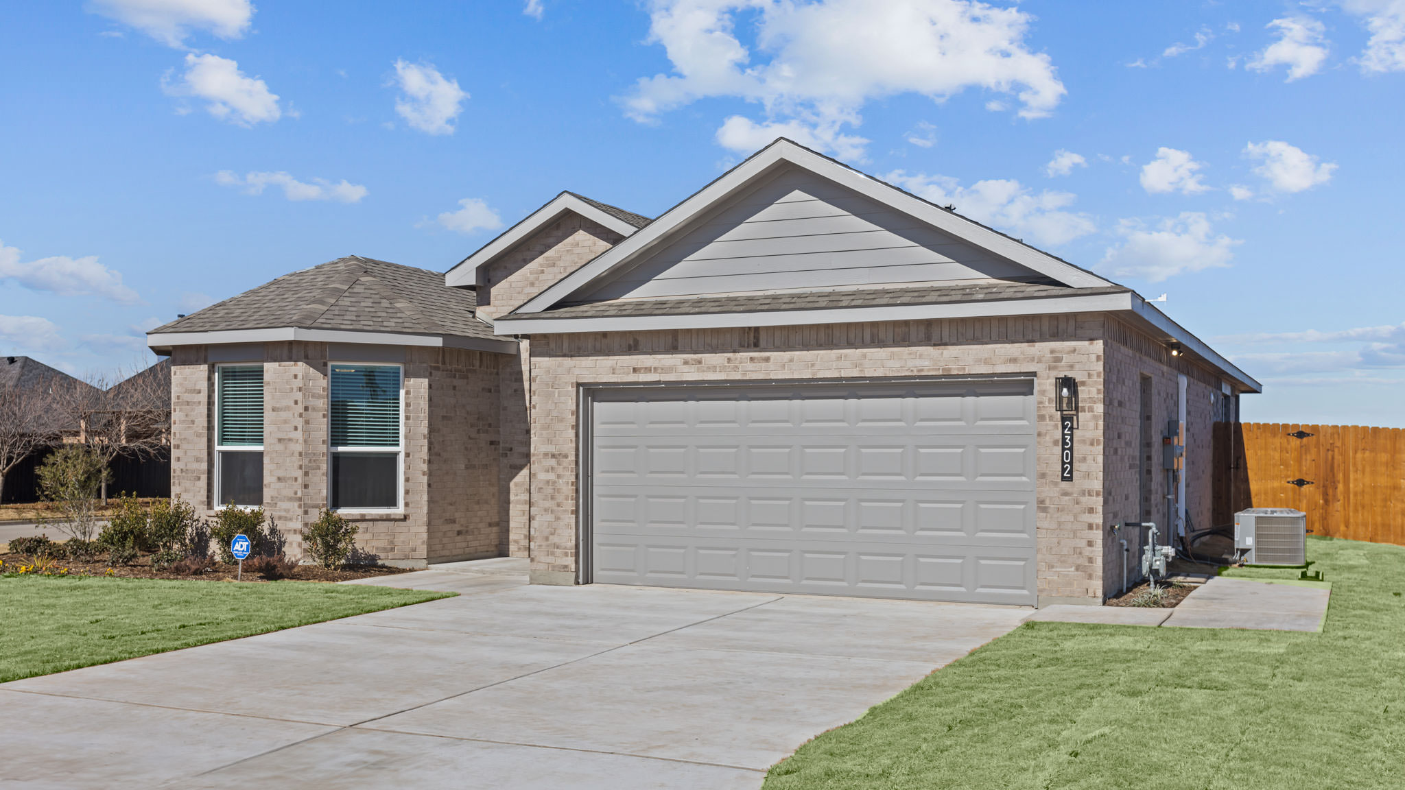 Exterior side view of single-story modern brick home with front entry and garage