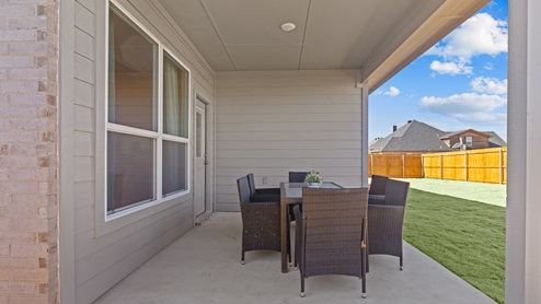 Covered back patio area overlooking backyard with grass