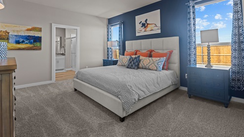 Spacious primary bedroom with dark blue accent wall and orange and gray colorful accents