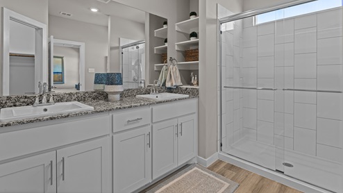 Primary bathroom attached to primary bedroom with built in vanity and walk-in shower space