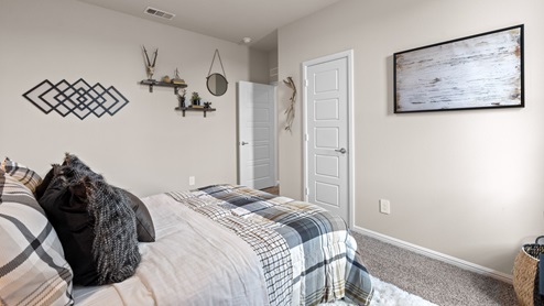 Guest bedroom with plush carpet floors and warm accent colors