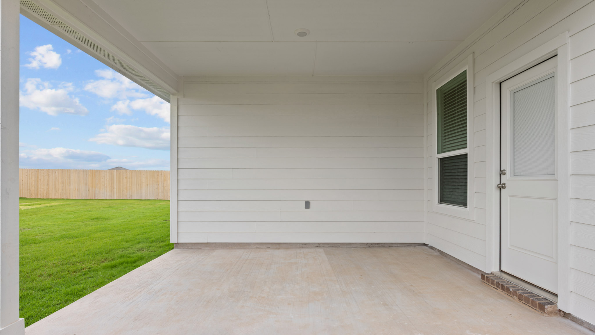 Covered back patio area overlooking spacious backyard