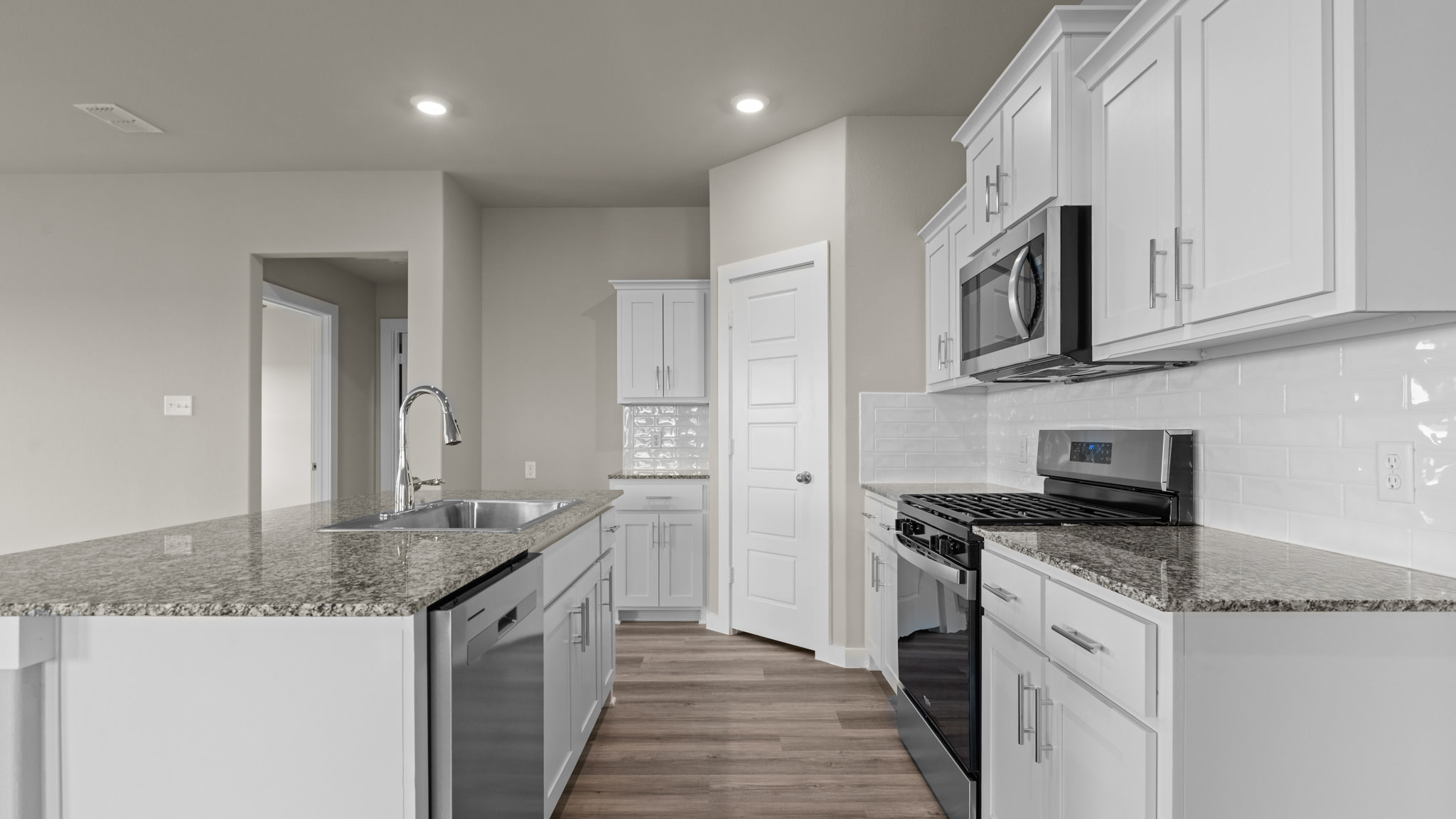 Open concept kitchen with stainless steel appliances, shaker style cabinets, and elevated finishes