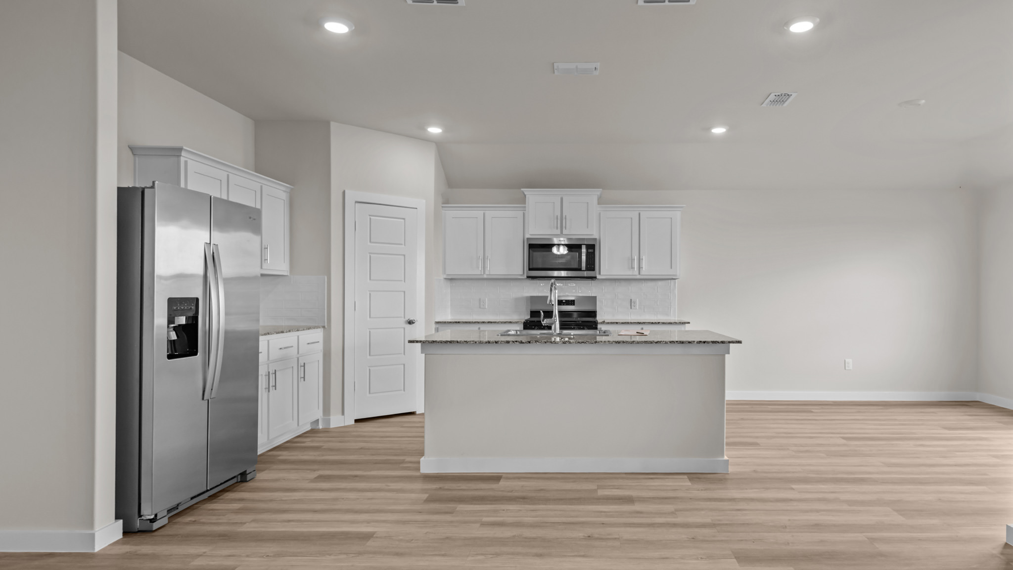 Open concept kitchen with stainless steel appliances, shaker style cabinets, and elevated finishes