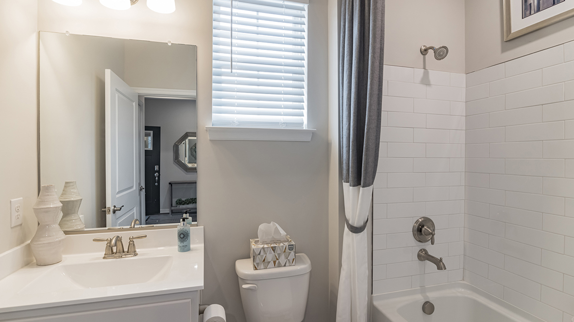 The second bathroom includes single white vanity and bathtub.