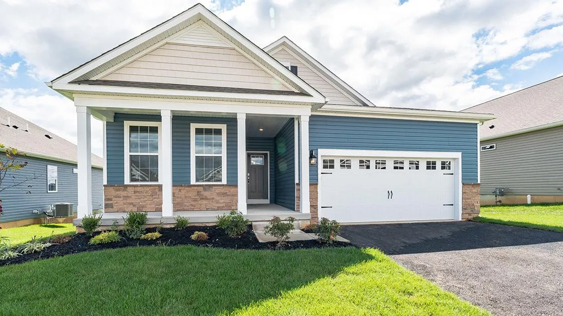 Exterior of one story greenish blue house with white two car garage.