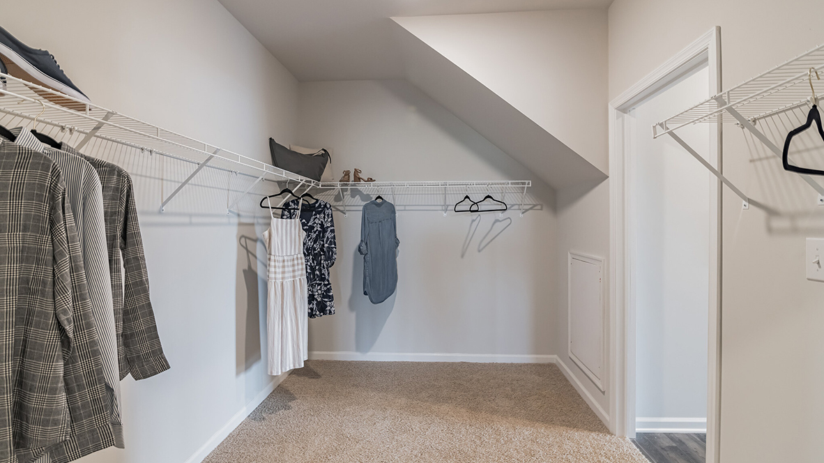 Spacious primary closet with racks and shelves connects to the primary bathroom and laundry room.
