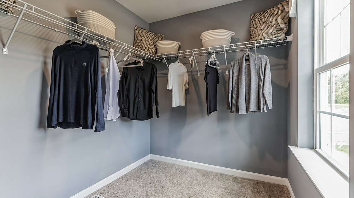 Large closet with shelves and racks and a single window.
