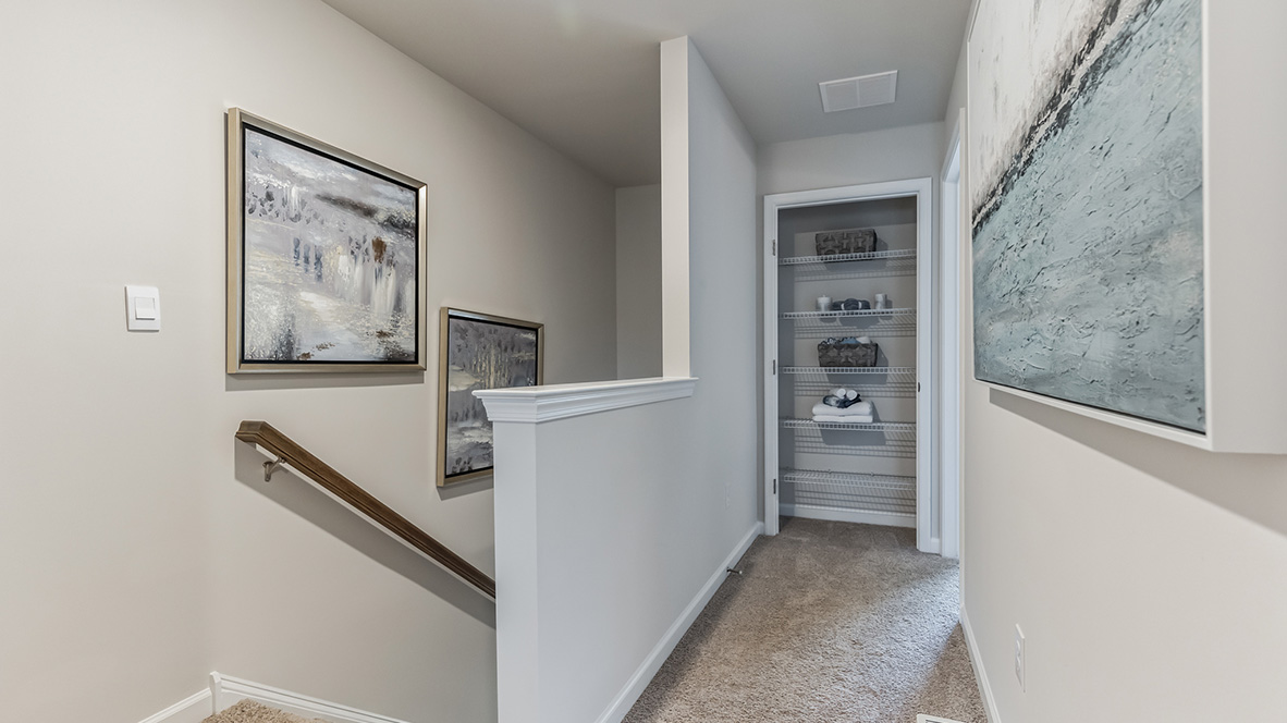 Top of the stairs looking down the hall to the extra closet next to the primary bedroom.
