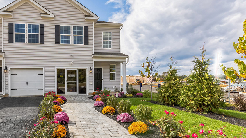 Exterior front image of the model townhome with white horizontal paneling with a white single car garage.